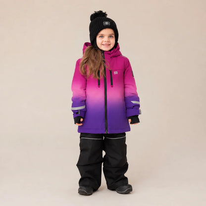 Habit de neige Brooklyn - Nanö à capuche dégradé rose et violet en matériau isolant, pour enfant fille, porté de face avec pantalon noir et bonnet noir.