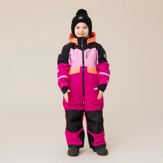 Enfant portant un Habite de neige 1 pièce performance rose - Nanö avec des teintes rose vif, rose pâle, noir et orange, en tissu imperméable, vue de face.