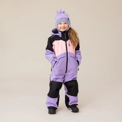 Enfant fille portant un Habit de neige 1 pièce performance - Nanö en violet, rose et noir, style combinaison, vue de face avec bonnet assorti.