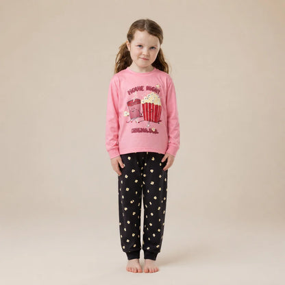 Pyjama - Nanö rose et noir pour fille avec motif popcorn sur le haut et pantalon imprimé porté de face par une enfant