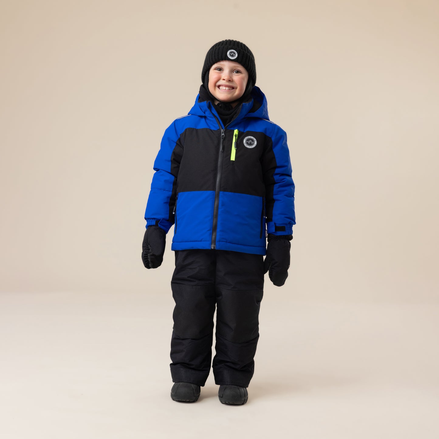 Enfant garçon habillé en Habit de neige - Peluche & Tartine bleu roi et noir avec bonnet noir, gants noirs, pantalon matelassé noir, vue de face.