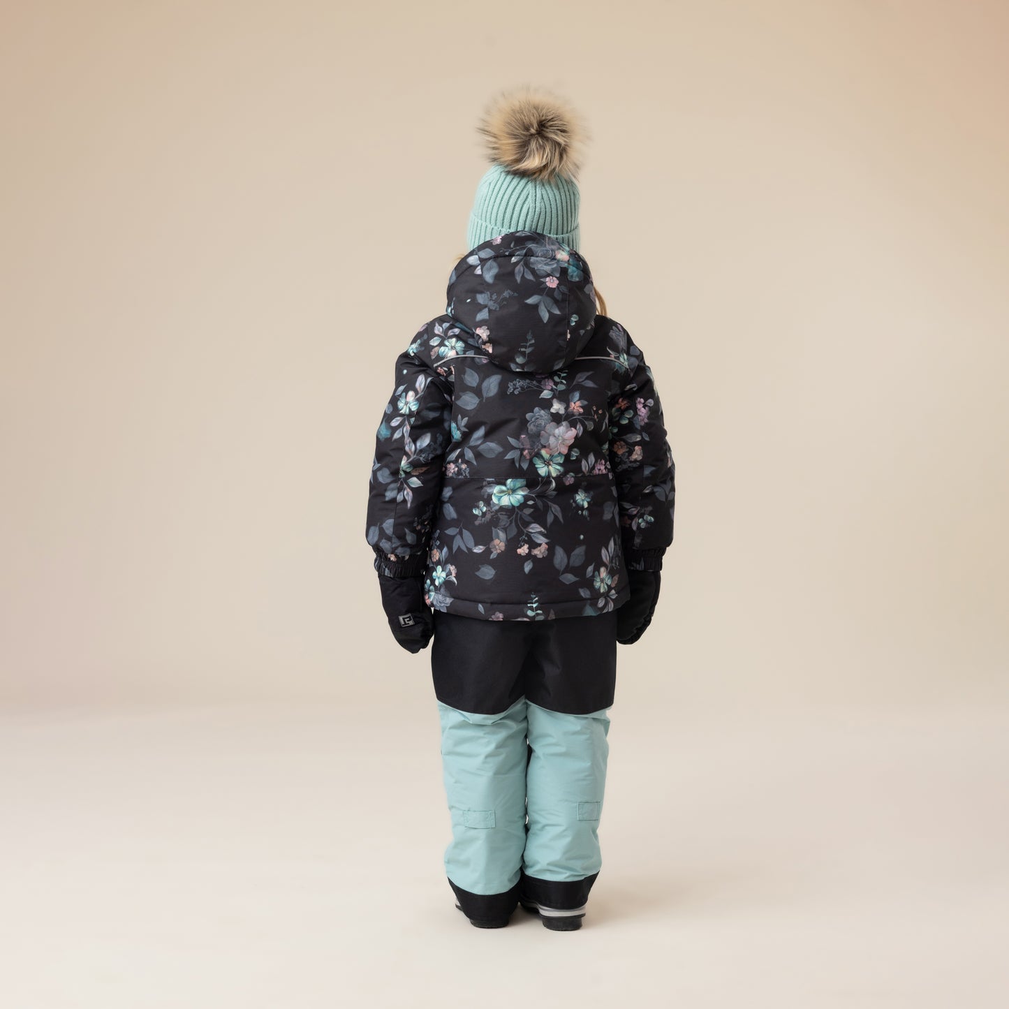 Habit de neige - Peluche & Tartine pour enfant fille, manteau noir à motifs floraux bleus et roses, pantalon bleu clair, vue de dos.