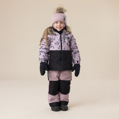 Enfant fille portant un habit de neige - Peluche & Tartine bicolore rose et noir avec motif floral, bonnet rose à pompon, vue de face.