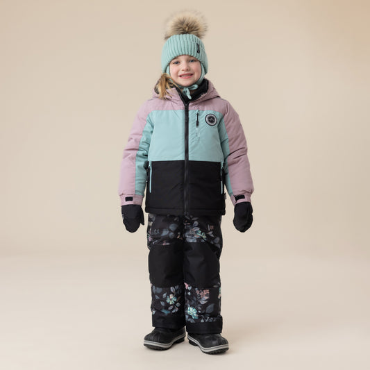 Habit de neige - Peluche & Tartine pour enfant, veste colorblock rose, bleu clair et noir avec pantalon noir à motifs floraux, vue de face, porté par une fille.
