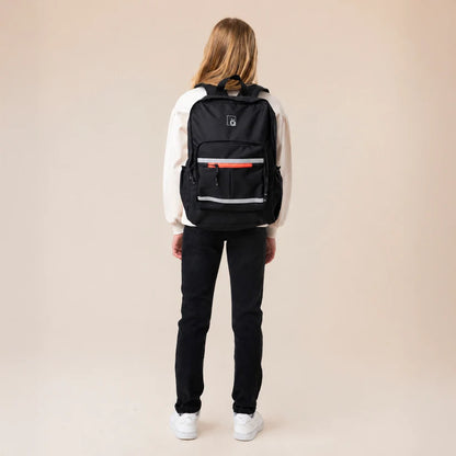 Sac à dos - Snö noir porté par une jeune femme vue de dos avec poches zippées et bandes réfléchissantes