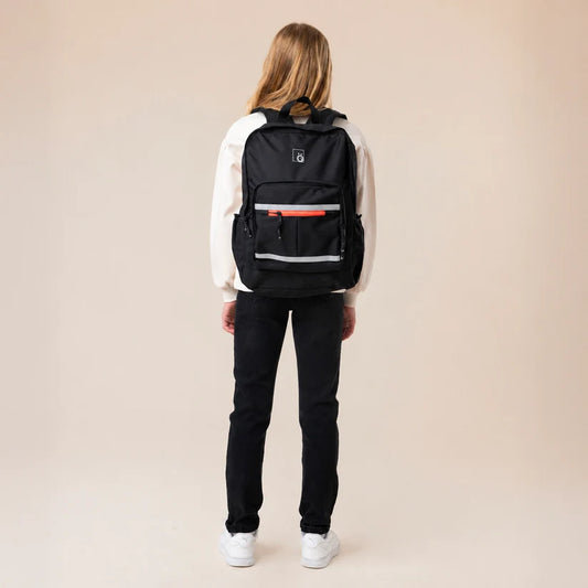 Sac à dos - Snö noir porté par une jeune femme vue de dos avec poches zippées et bandes réfléchissantes