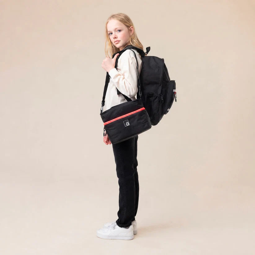Boîte à lunch - Snö noire portée en bandoulière par une fille avec sac à dos noir vue de profil