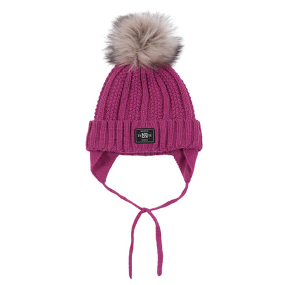Tuque d'hiver - Nanö rose avec pompon en fausse fourrure beige, tricotée avec cache-oreilles et cordons, vue de face.