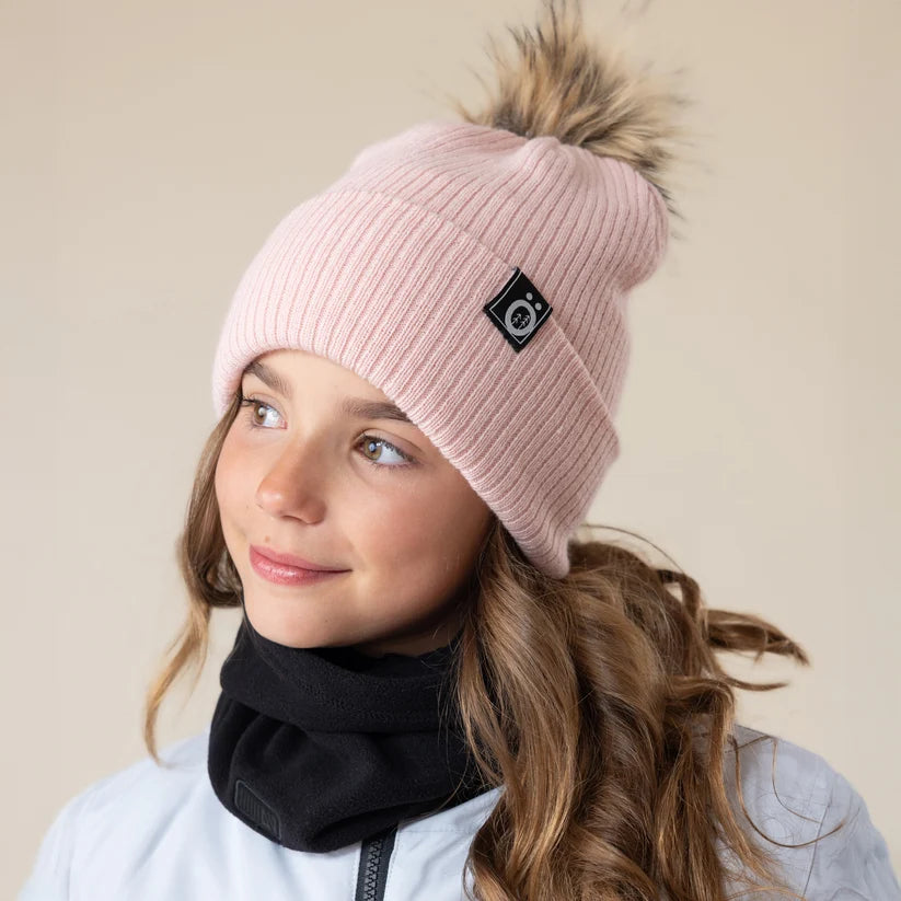 Tuque d'hiver - Snö rose pâle en tricot côtelé avec pompon en fausse fourrure portée par une fille vue de trois quarts