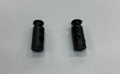 Pinces à ressorts pour lacets noires en plastique, avec mécanisme à ressorts visible, vue de dessus, paire unique.