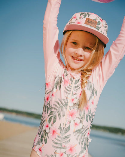Casquette - Deux Par Deux rose à imprimé fleurs vertes et roses portée par enfant fille, vue de face en extérieur plage