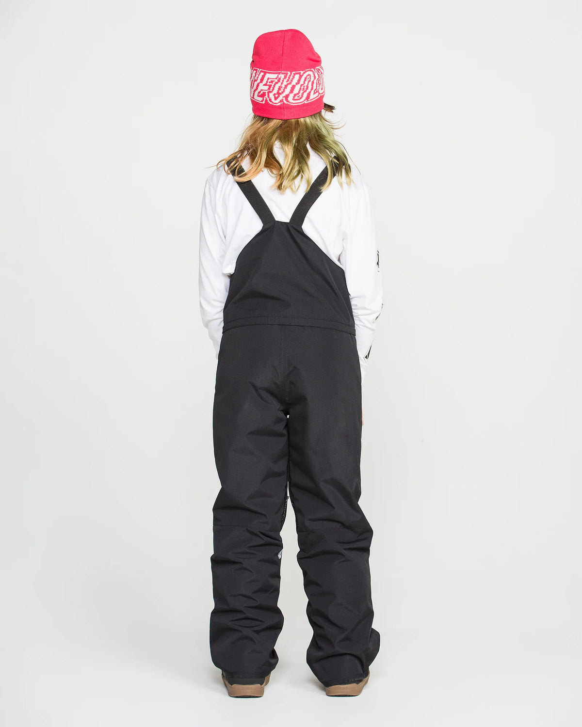 Salopette de neige Barkley Ins Bib - Volcom noire portée par une fille, vue de dos, avec bretelles croisées et bonnet rose.