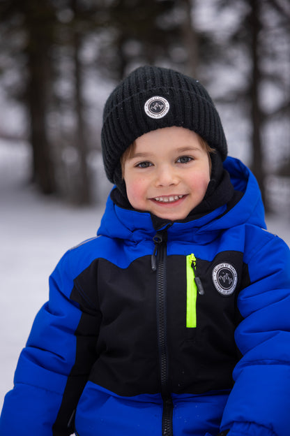 Habit de neige - Peluche & Tartine bleu et noir avec zip jaune fluo, pour enfant, porté par un garçon, vue de face en extérieur hivernal.