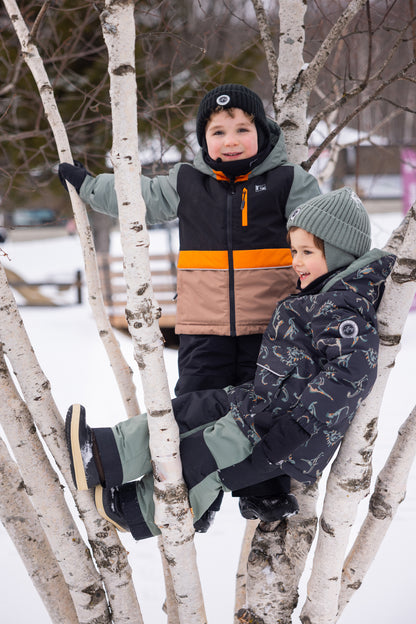 Habit de neige - Peluche & Tartine pour enfant, combinaison multicolore avec noir, orange, beige et motifs nature, portée en extérieur hivernal, vue de face et de profil.