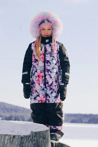 Habit de neige Play - Deux Par Deux pour fille aux motifs floraux roses et mauves avec capuchon bordé de fourrure vue de face dans la neige