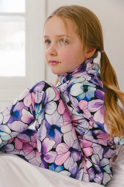 Sous-vêtements thermiques - Deux Par Deux pour enfant fille, motif fleur multicolore rose, violet et bleu, en tissu extensible, vue de profil porté assise.