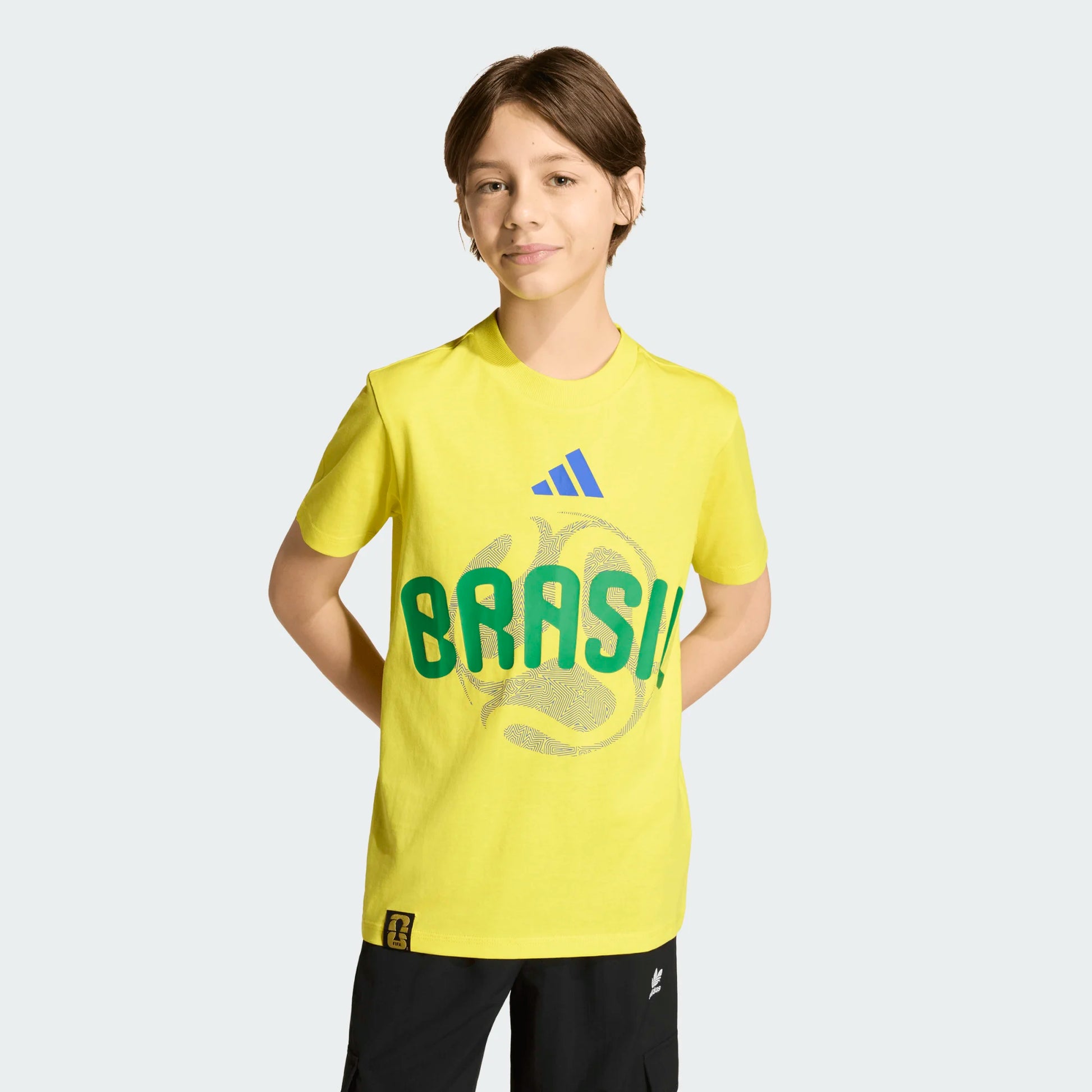 T-Shirt FIFA World Cup 26 Brazil - Adidas jaune avec logo vert et bleu, coton, garçon, porté de face, fond clair.