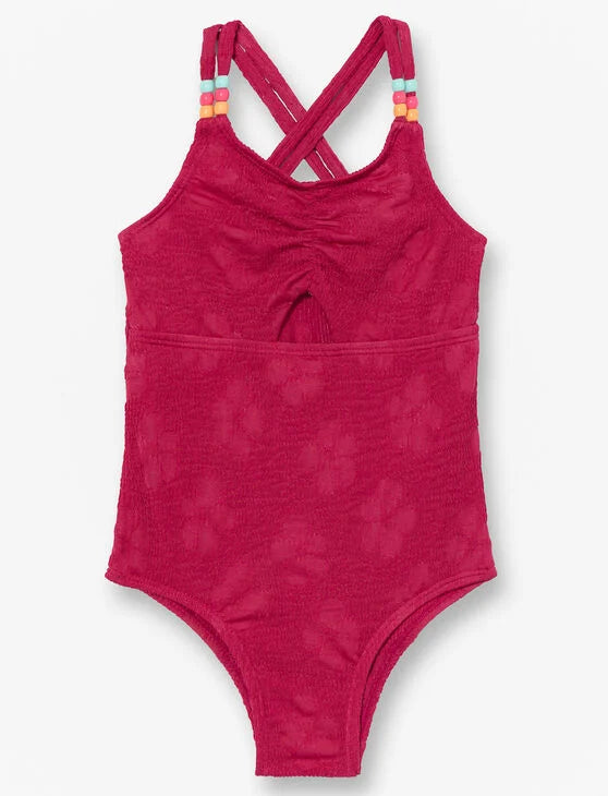 Maillot de bain - M.I.D. rose fuchsia en tissu texturé à motifs floraux, bretelles croisées avec perles, vue de face enfant fille.
