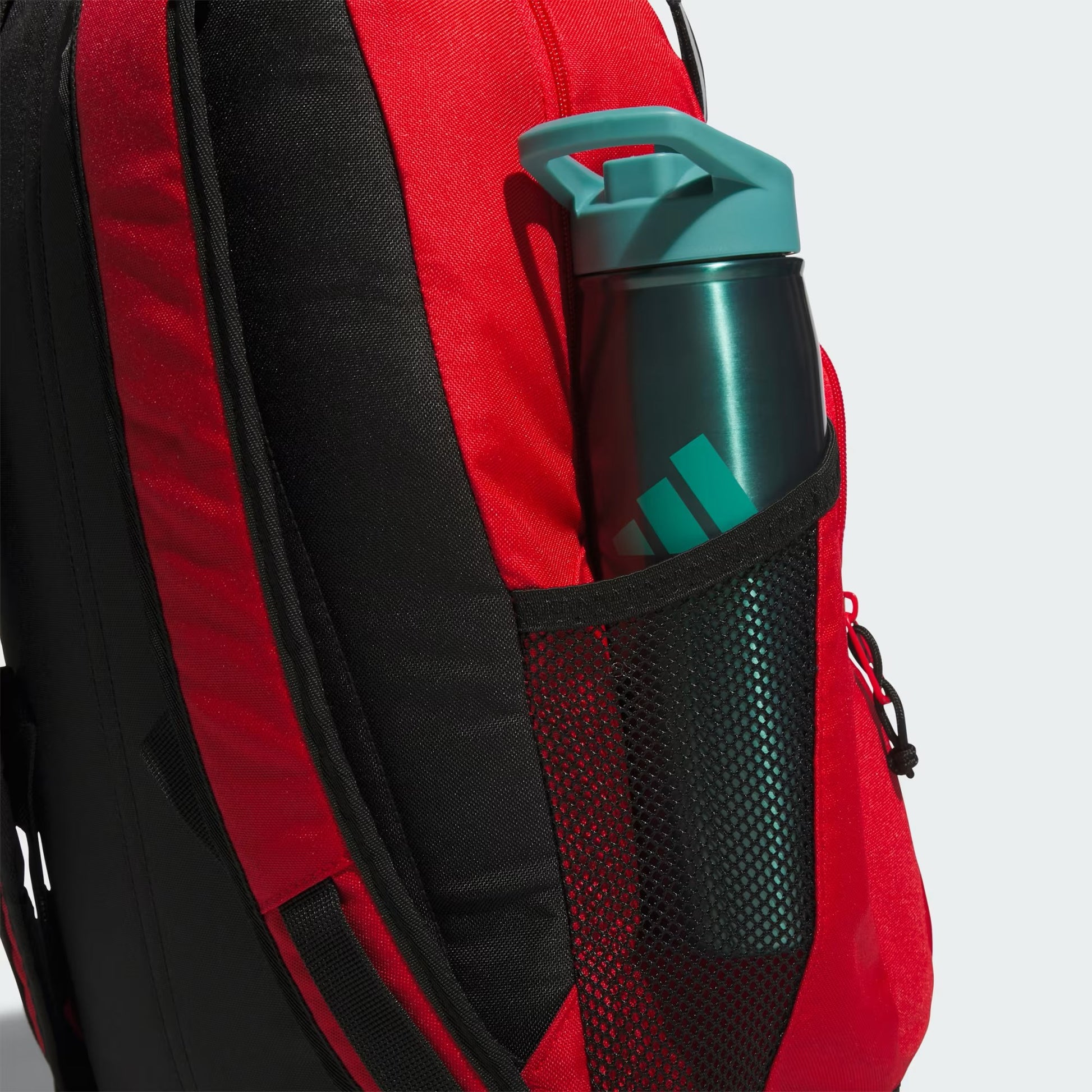 Sac à dos - Adidas rouge et noir en textile avec poche latérale en filet, vue de détail sur la bouteille placée dans le compartiment.