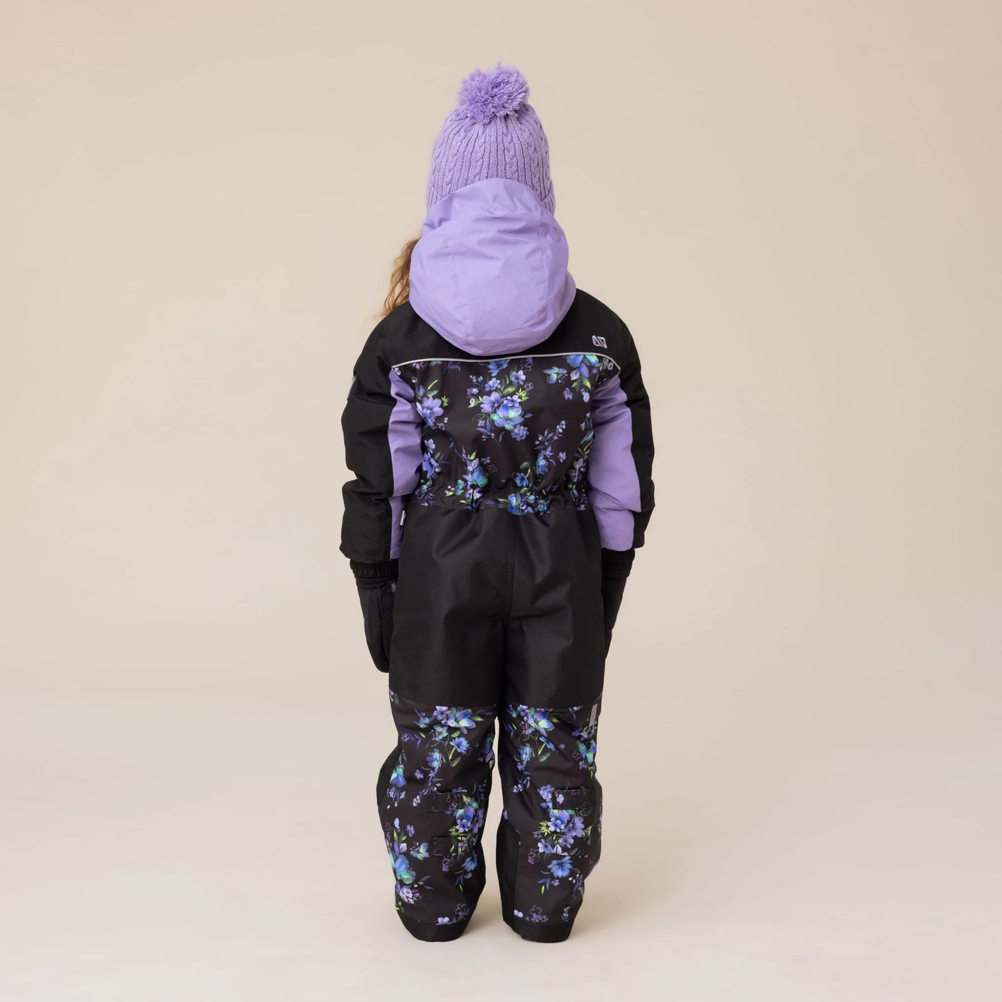 Habit de neige 1 pièce Emma - Nanö noir avec motifs floraux violets et bleus, capuche et manches violettes, pour enfant, vue de dos porté sur mannequin.