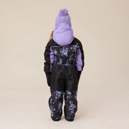 Habit de neige 1 pièce Emma - Nanö noir avec motifs floraux violets et bleus, capuche et manches violettes, pour enfant, vue de dos porté sur mannequin.