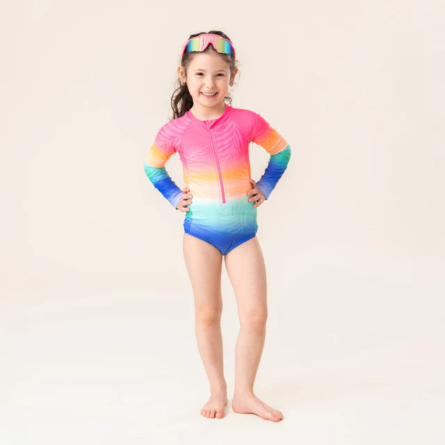 Maillot de bain - Nanö une pièce manches longues dégradé rose, orange, jaune, bleu, pour fille, porté sur mannequin, vue de face.
