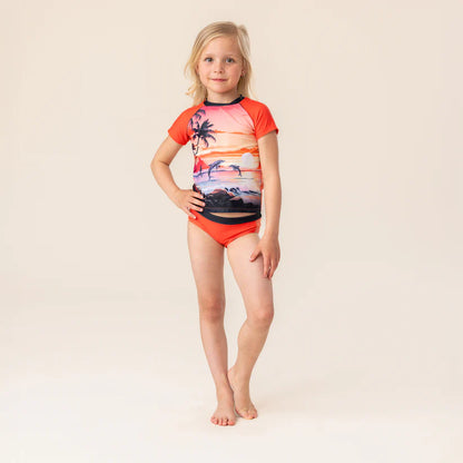 Maillot de bain - Nanö pour enfant fille, deux pièces orange avec motif coucher de soleil et palmier, vue de face porté.