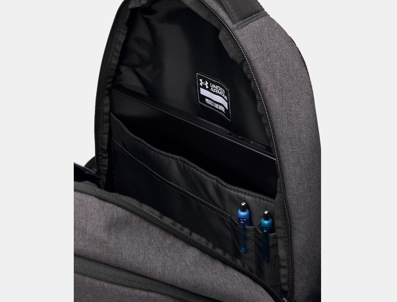 Sac à dos UA Hustle 6.0 - Under Armour gris foncé en polyester avec poche intérieure organisée contenant un ordinateur portable, vue de l'intérieur.