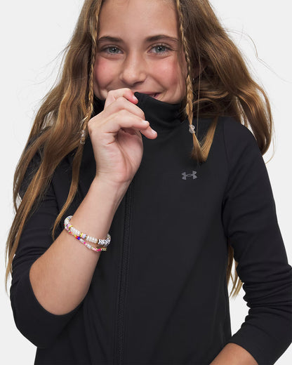 Veste UA Motion - Under Armour noire en textile léger, manches longues, portée par une enfant vue de face serrant le col.