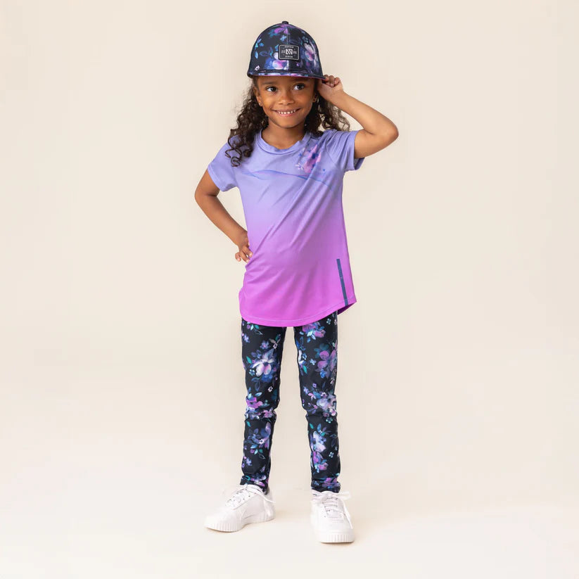 Legging - Nanö imprimé floral bleu et violet porté par enfant fille, vue de face, tissu tricot double ajusté.