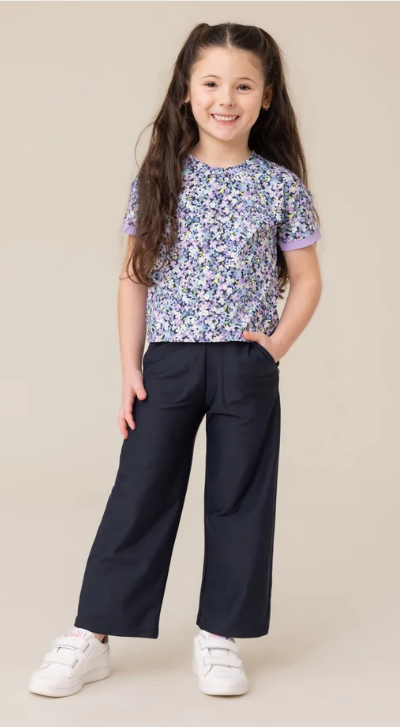 Fille enfant portant un pantalon athlétique Marine - Nanö bleu marine en tissu léger, vue de face, avec un t-shirt à motifs floraux lilas et blancs.