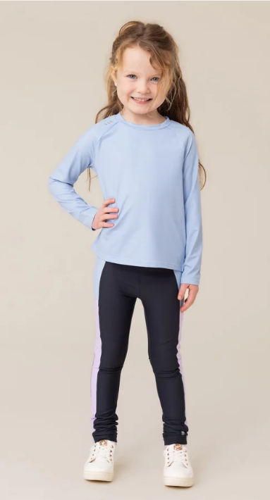 T-shirt athlétique manches longues - Nanö bleu clair en tissu technique, porté par une fillette, vue de face avec manches raglan ajustées.