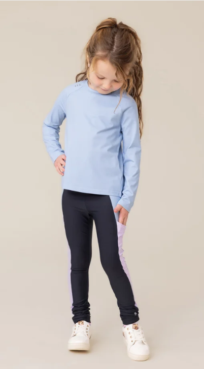 Fille portant un Leggin athlétique Marine - Nanö noir avec bandes latérales violettes, vue de face, en tenue sportive avec un haut bleu clair manches longues.