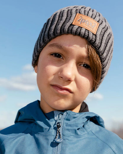 Tuque Mi-Saison - Deux Par Deux en coton côtelé gris avec écusson logo, portée par enfant, vue de face, extérieur ciel bleu.