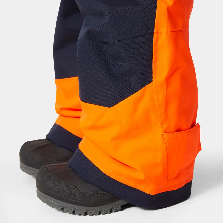 Salopette de neige - Helly Hansen orange fluo et bleu marine, tissu imperméable, détail bas jambes, pour enfant, vue rapprochée.