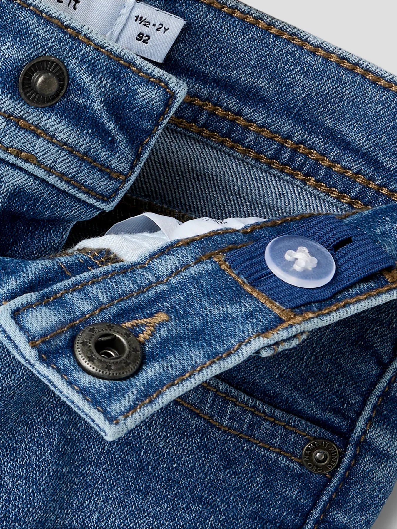 Jeans - Name It en denim bleu clair avec bouton pression et bouton ajustable, pour garçon, détail taille et couture.