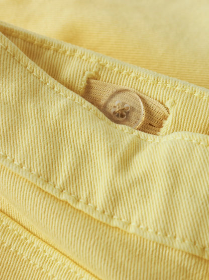 Détail d'un bouton transparent sur tissu jaune en coton, pour Short - Name It, vue rapprochée.