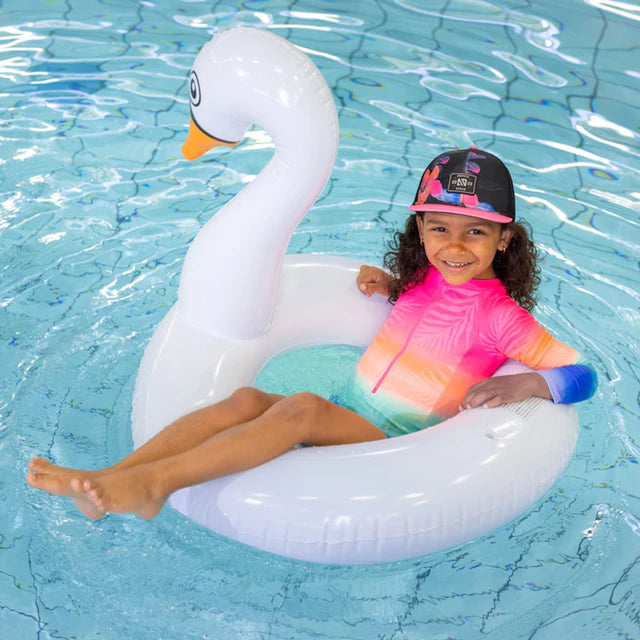Casquette - Nanö noire avec visière rose et motifs fleuris, portée par enfant, vue de face en piscine.