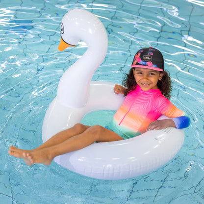 Casquette - Nanö noire avec visière rose et motifs fleuris, portée par enfant, vue de face en piscine.