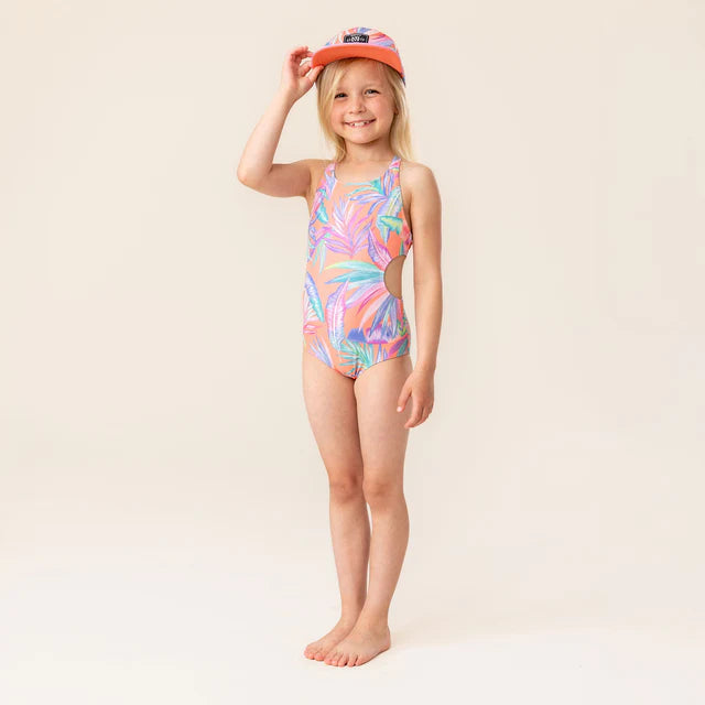 Fille portant une Casquette - Nanö saumon, vue de face, avec maillot de bain coloré et motif tropical, sourire naturel.