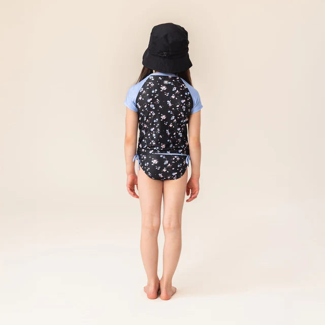 Maillot de bain - Nanö, ensemble noir avec motifs floraux blancs et bleus, manches courtes bleues, pour enfant fille, vue de dos.