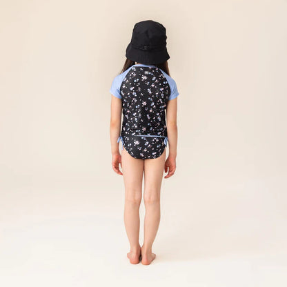 Maillot de bain - Nanö, ensemble noir avec motifs floraux blancs et bleus, manches courtes bleues, pour enfant fille, vue de dos.