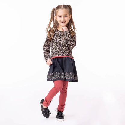 Tunique - Nanö en jersey imprimé marron et jupe noire avec motifs colorés, manches longues froncées, portée par fille, vue de face