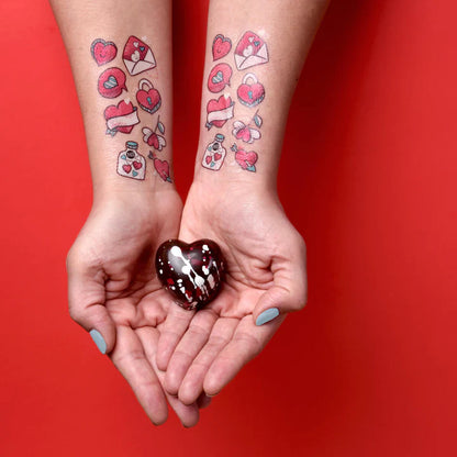 Pico Tatoo - Saint-Valentin tatouages temporaires rouges et roses sur avant-bras, motifs cœurs et enveloppes, vue portée sur peau adulte