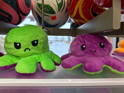 Pieuvre En Peluche Réversible verte et violette en tissu doux pour enfant, vue de face avec expressions faciales opposées.