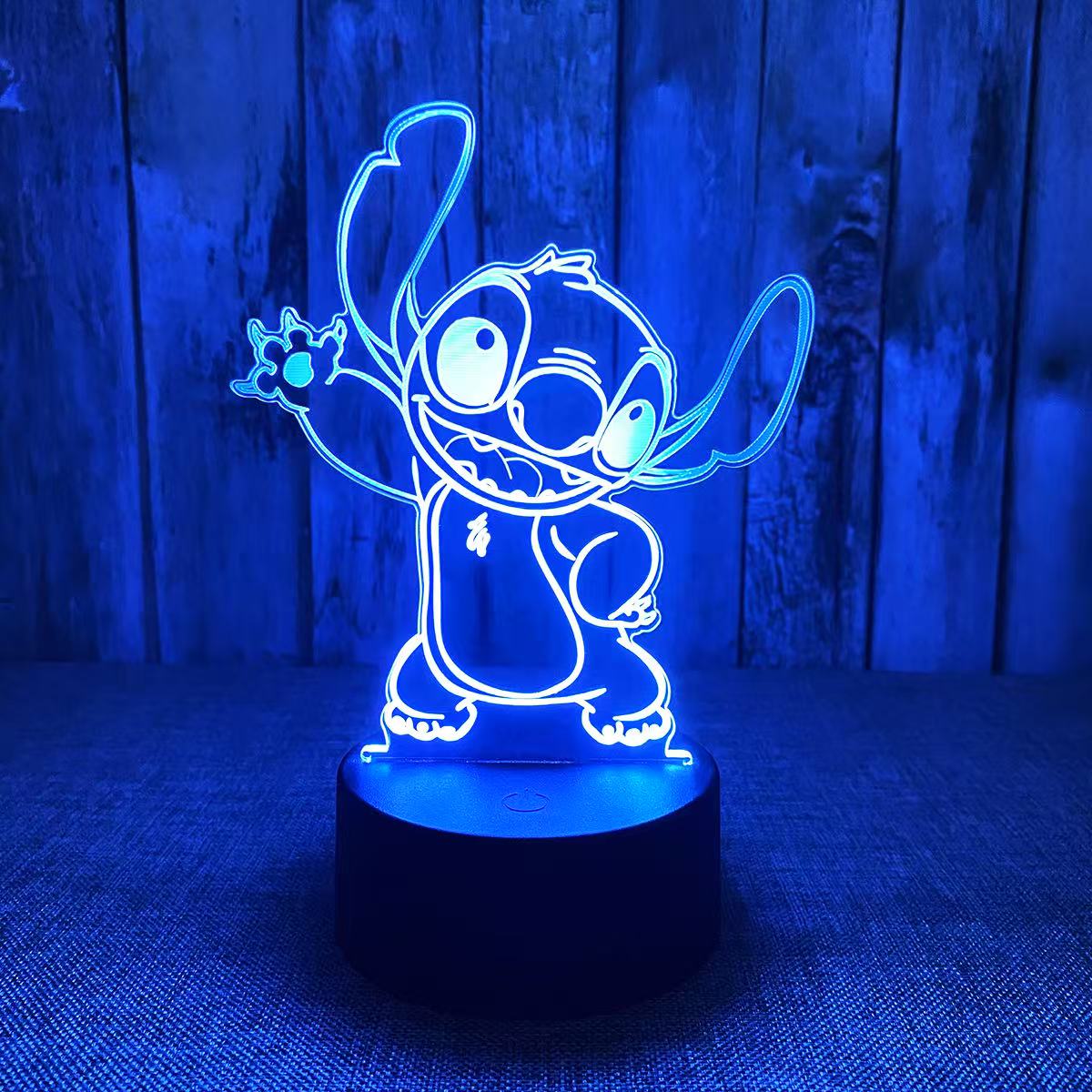 Lampe de Nuit Stitch LED bleue transparent, style cartoon, pour enfant, vue de face avec base noire ronde.