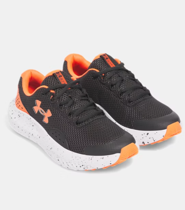 Espadrilles UA Surge 4 - Under Armour noires et orange, mesh respirant, semelle blanche tachetée, pour enfant, vue de trois quarts face.