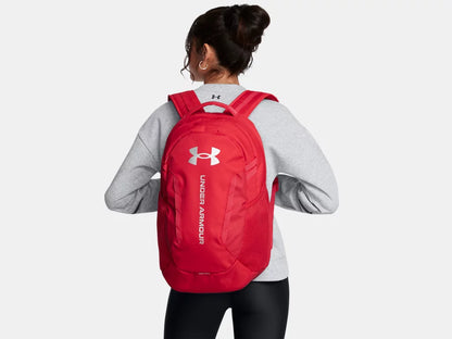Sac à dos - Under Armour rouge en tissu résistant à l'eau, style sport, porté par une femme, vue de dos