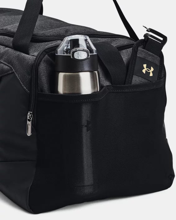 Sac sport - Under Armour noir avec compartiment latéral en filet, détail sur la gourde et logo doré, vue rapprochée.