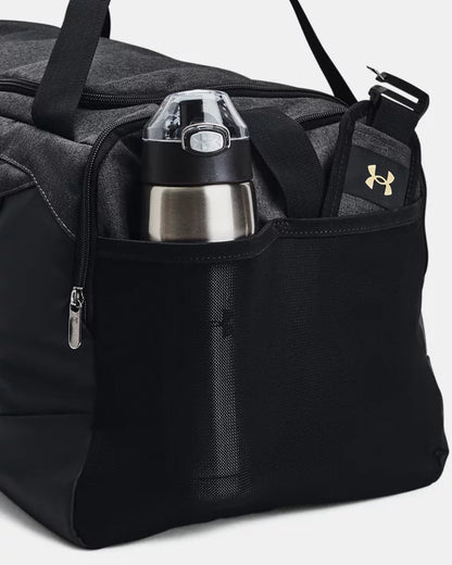 Sac sport - Under Armour noir avec compartiment latéral en filet, détail sur la gourde et logo doré, vue rapprochée.